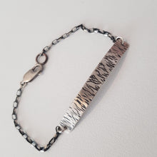Load image into Gallery viewer, Bracelet with textured metal band and chain on a light gray background
